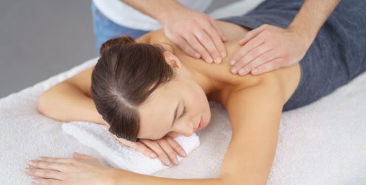 A person receiving a Tui-Na massage on their back, with hands applying pressure to the shoulders.